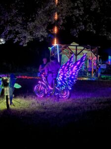 Spectacular art bike with illuminated purple butterfly wings and LED-wrapped wheels at night festival
