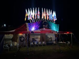 Northwest Mist theme camp with illuminated international flags, red and white striped tent, and colorful light projections