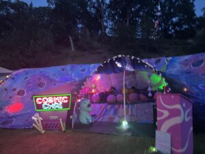Cosmic Chai theme camp with neon sign, space-themed fabric covering, plush seating area, and colorful lighting