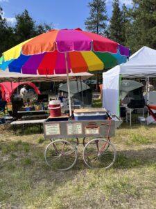 Pickleodeon pickle cart with colorful rainbow umbrella displaying brunch and happy hour cocktail menus at SOAK festival