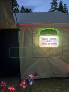 Pickleodeon outdoor movie theater tent at dusk with glowing marquee sign and LED flower lights