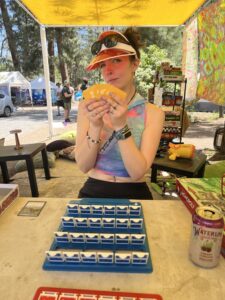 estival attendee in orange visor holding cards while playing Guess Who board game at theme camp
